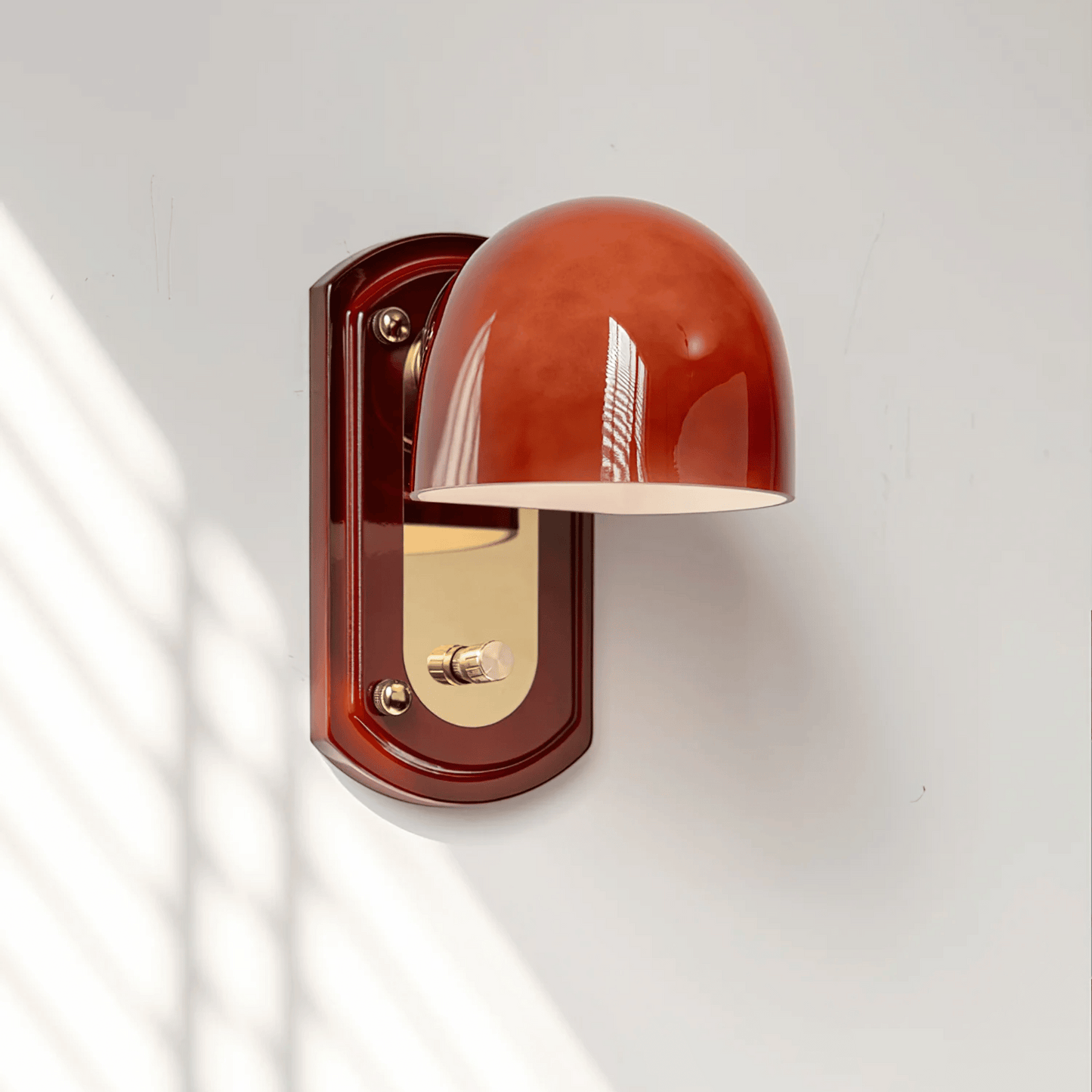 Wall-mounted light fixture with a red glass shade on a white wall
