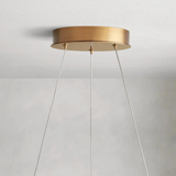 Gold ceiling light fixture with white cables on a plain background