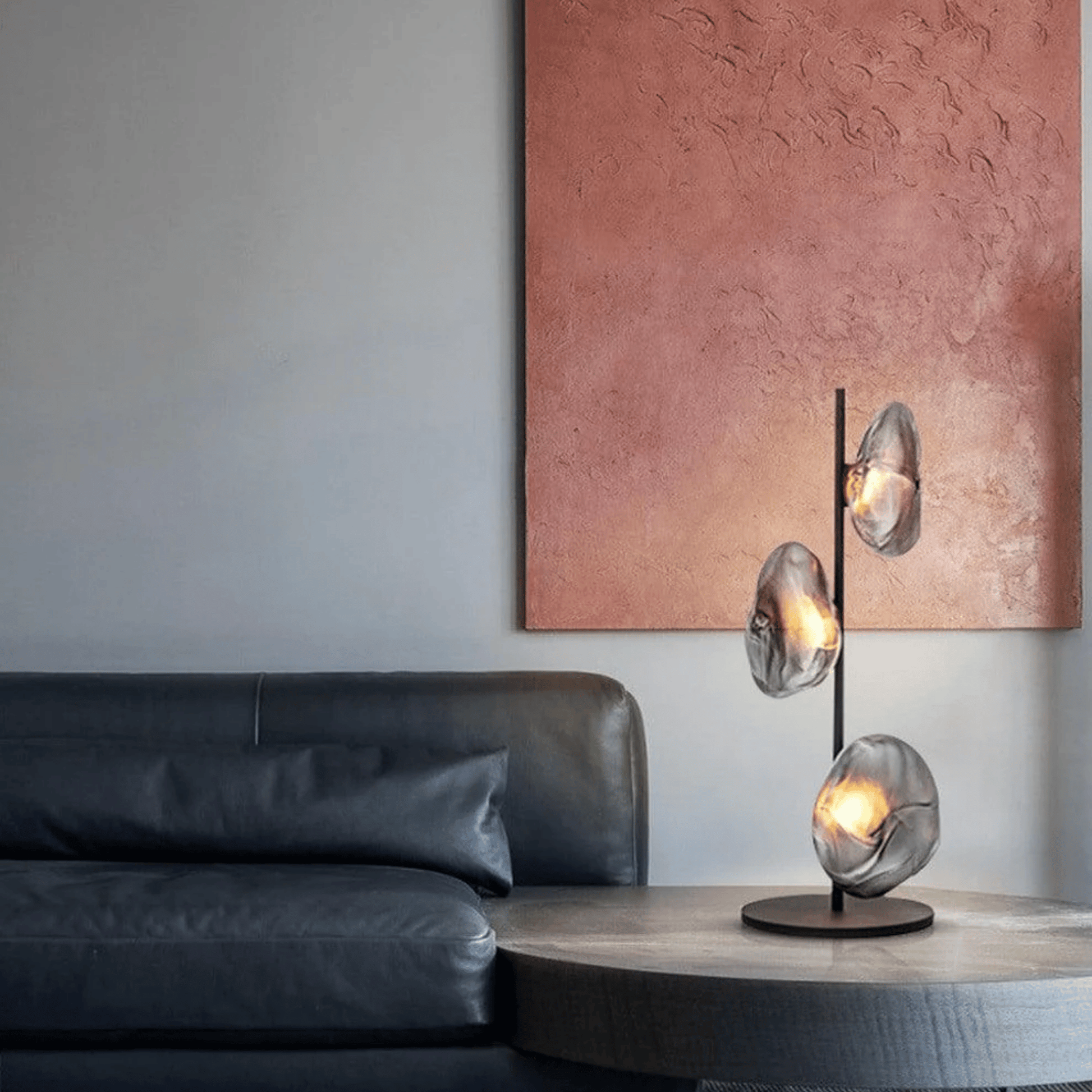 Modern interior with a black leather sofa and a decorative table lamp on a wooden side table.
