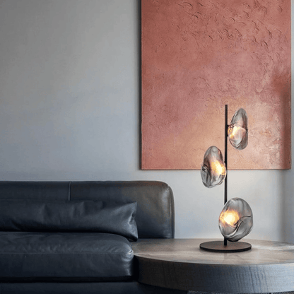Modern interior with a black leather sofa and a decorative table lamp on a wooden side table.