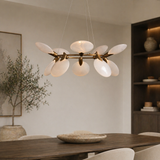 Modern chandelier hanging above a dining table in a room with neutral decor.