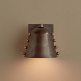 Bronze wall sconce with a warm glow on a beige wall