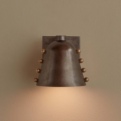 Bronze wall sconce with a warm glow on a beige wall