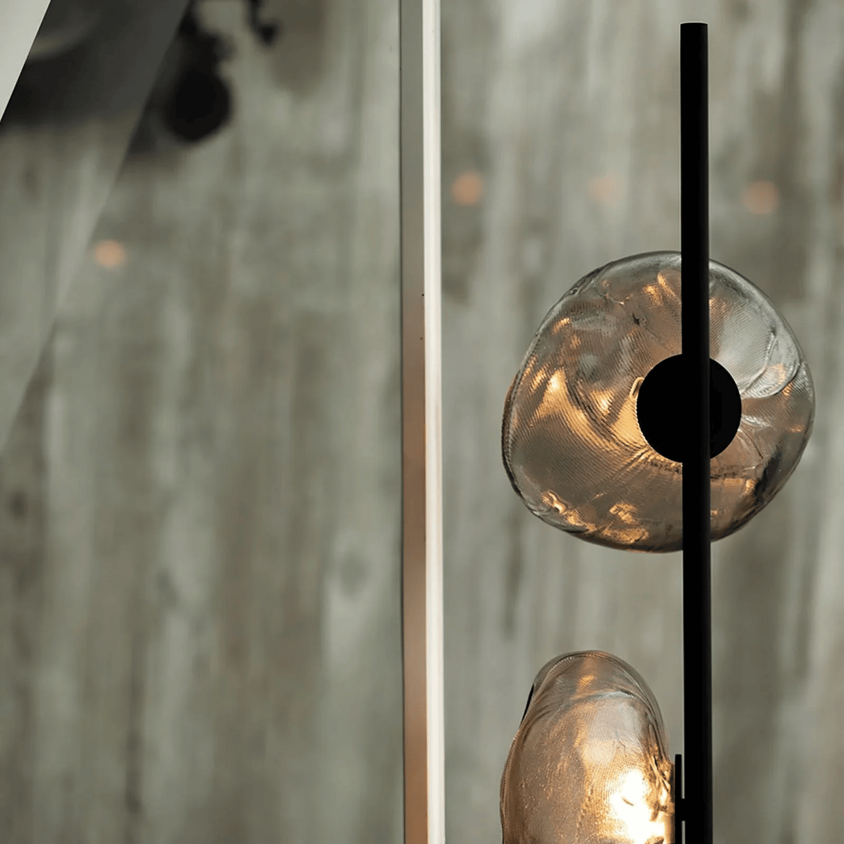 Close-up of a modern light fixture with glass shades and a black metal arm.