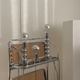 Chrome bar cart with three glass light bulbs on a neutral background