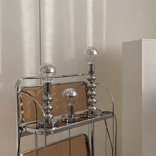 Chrome bar cart with three glass light bulbs on a neutral background