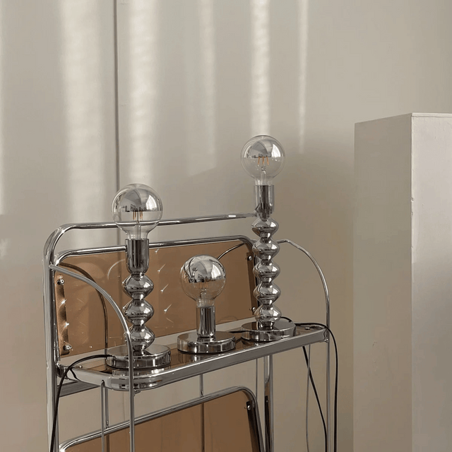 Chrome bar cart with three glass light bulbs on a neutral background