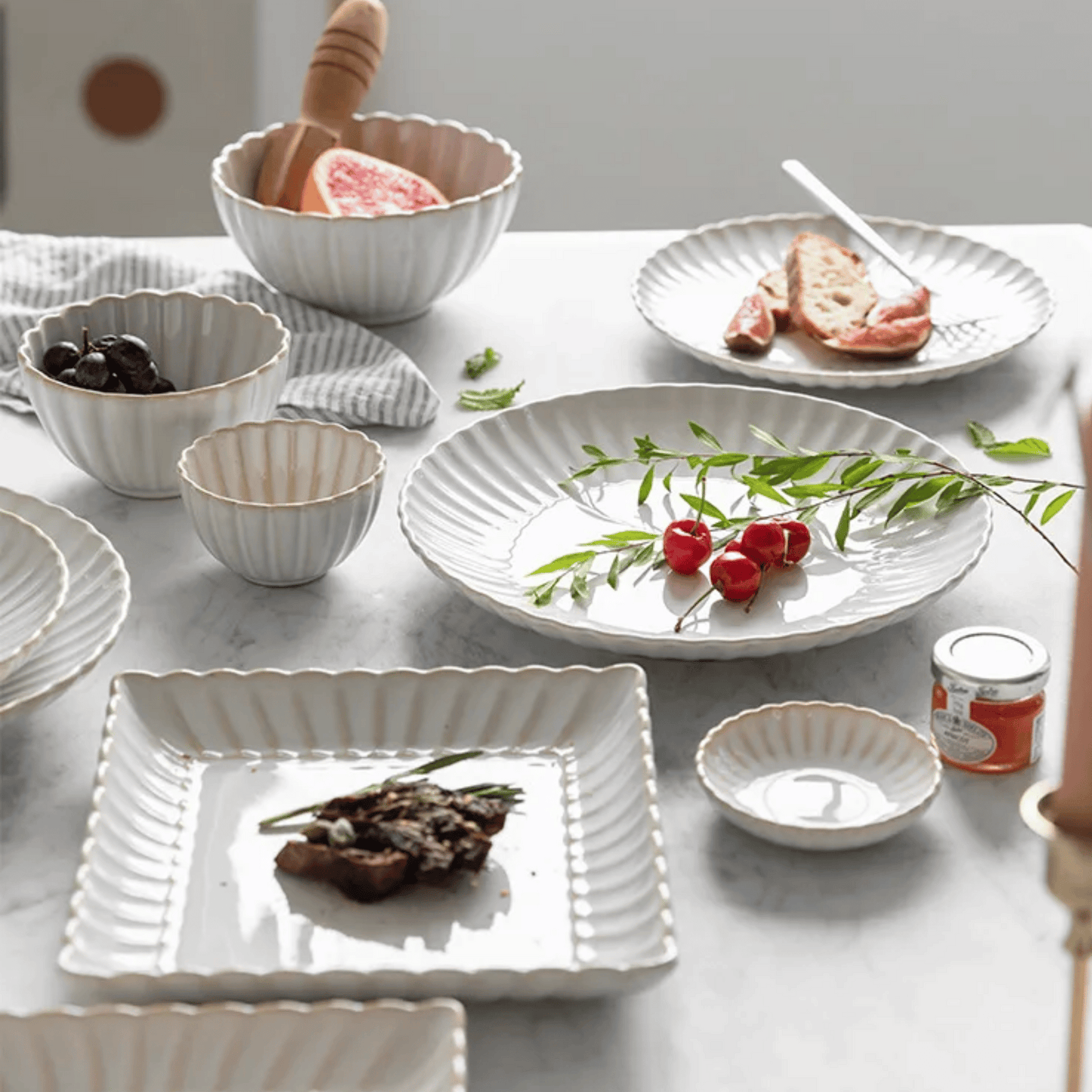 Set of white ceramic dishes on a table with food and garnishes.