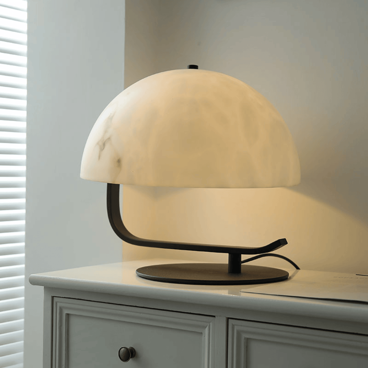 Table lamp with a marble-like shade on a white surface