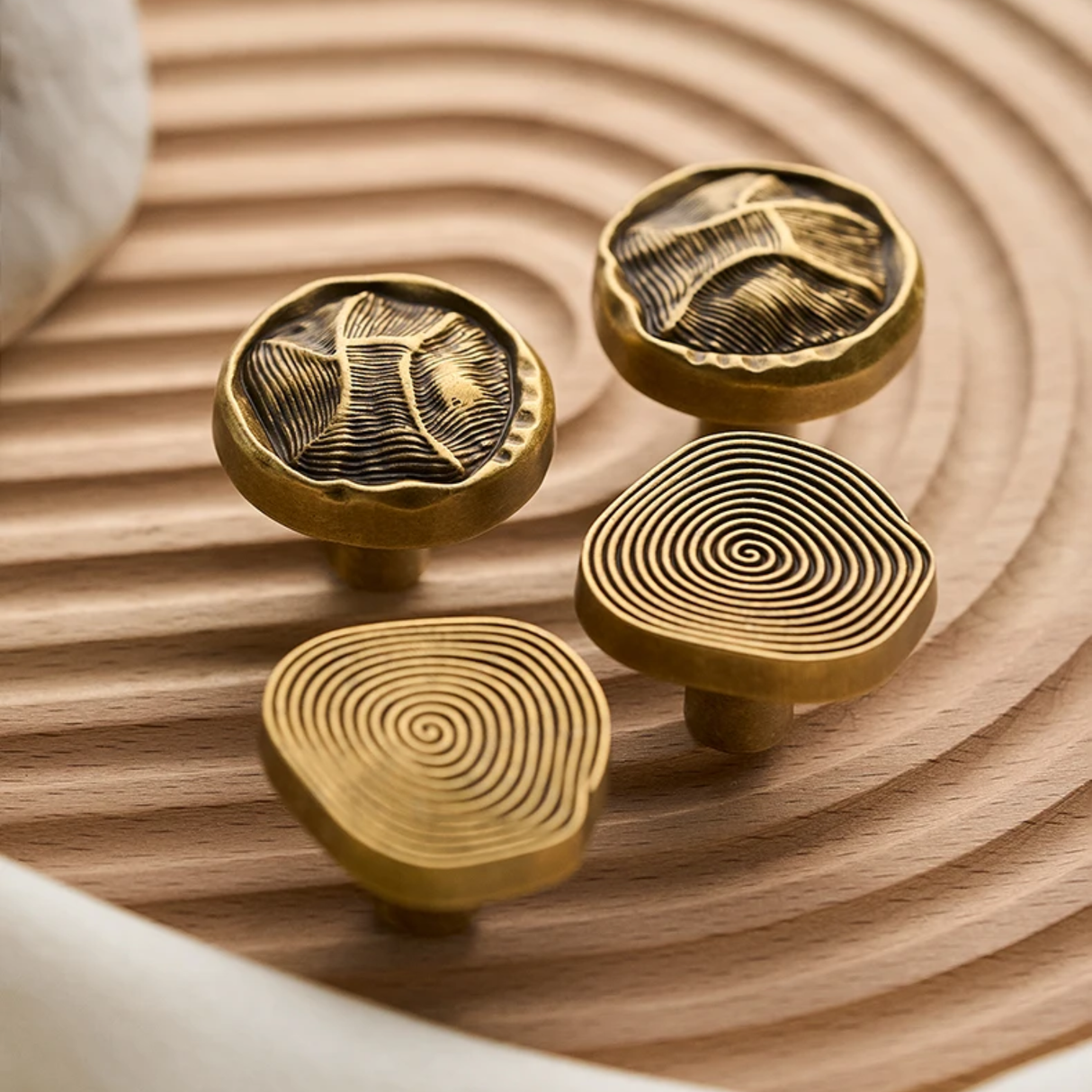 Four gold cabinet knobs with spiral patterns on a wooden surface