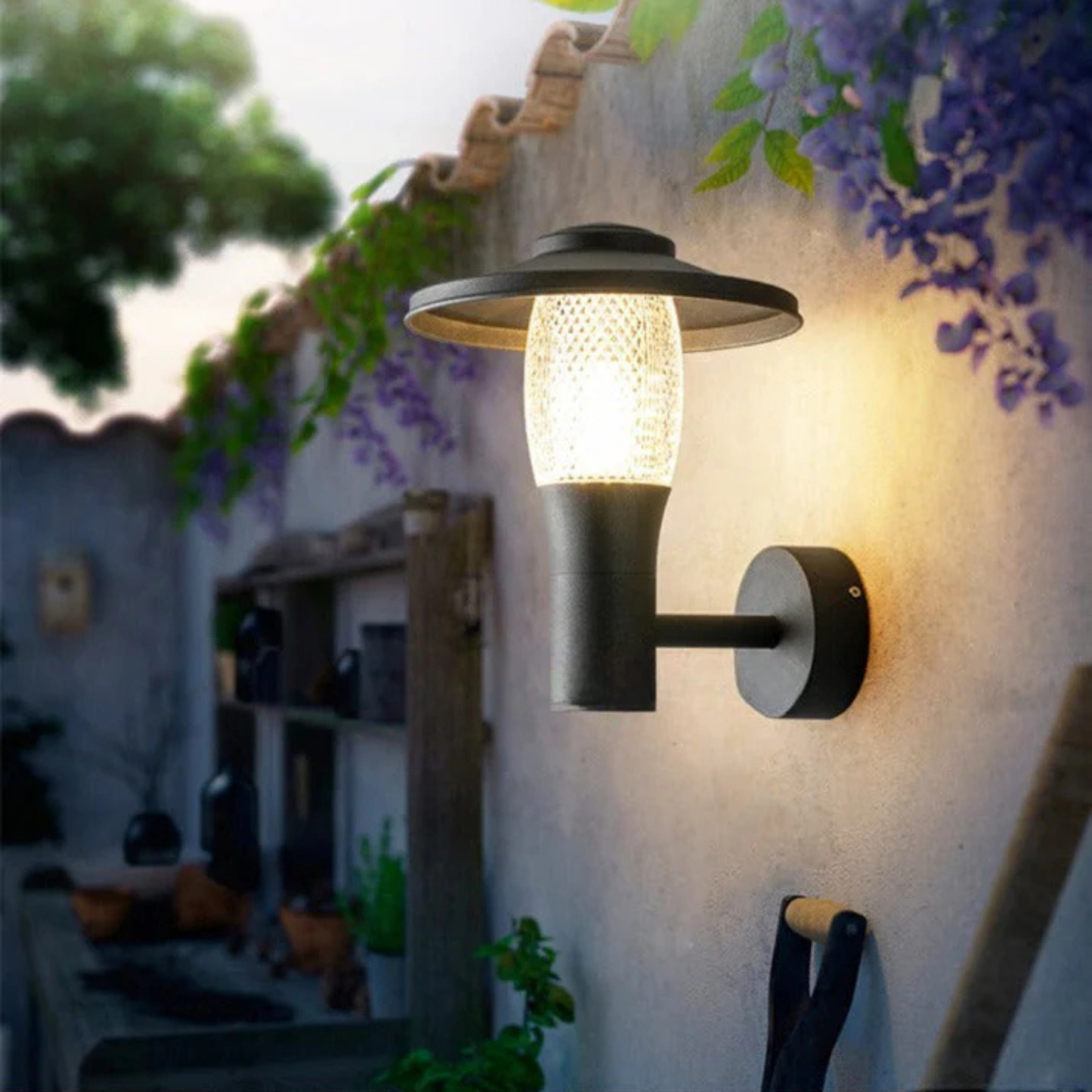 Stylish black wall lantern glowing softly on a white exterior wall near blooming purple vines