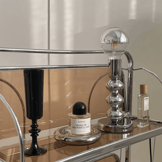 Perfume bottle on a table with a lamp and mirror in the background