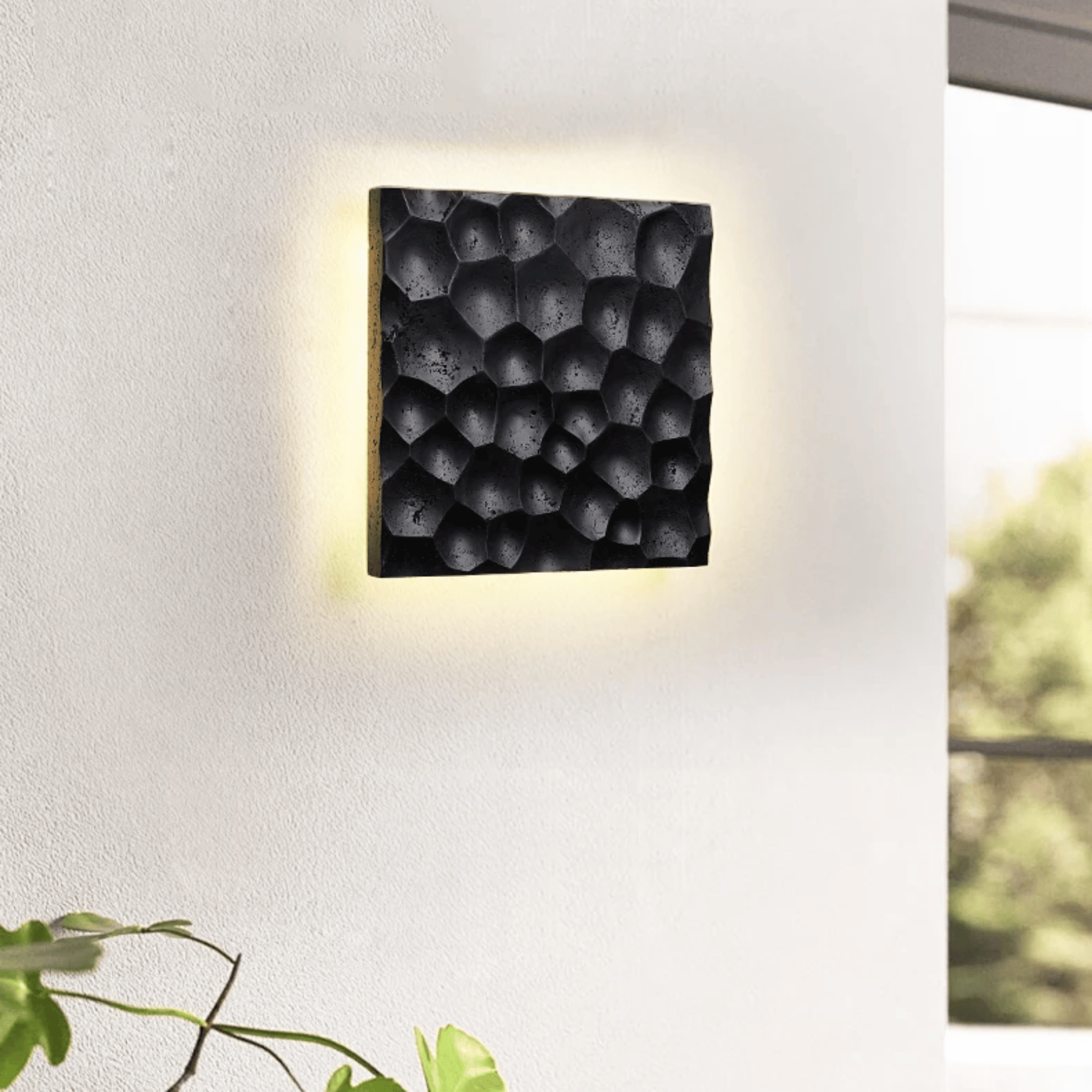 Modern wall light fixture with textured black surface on a white wall.