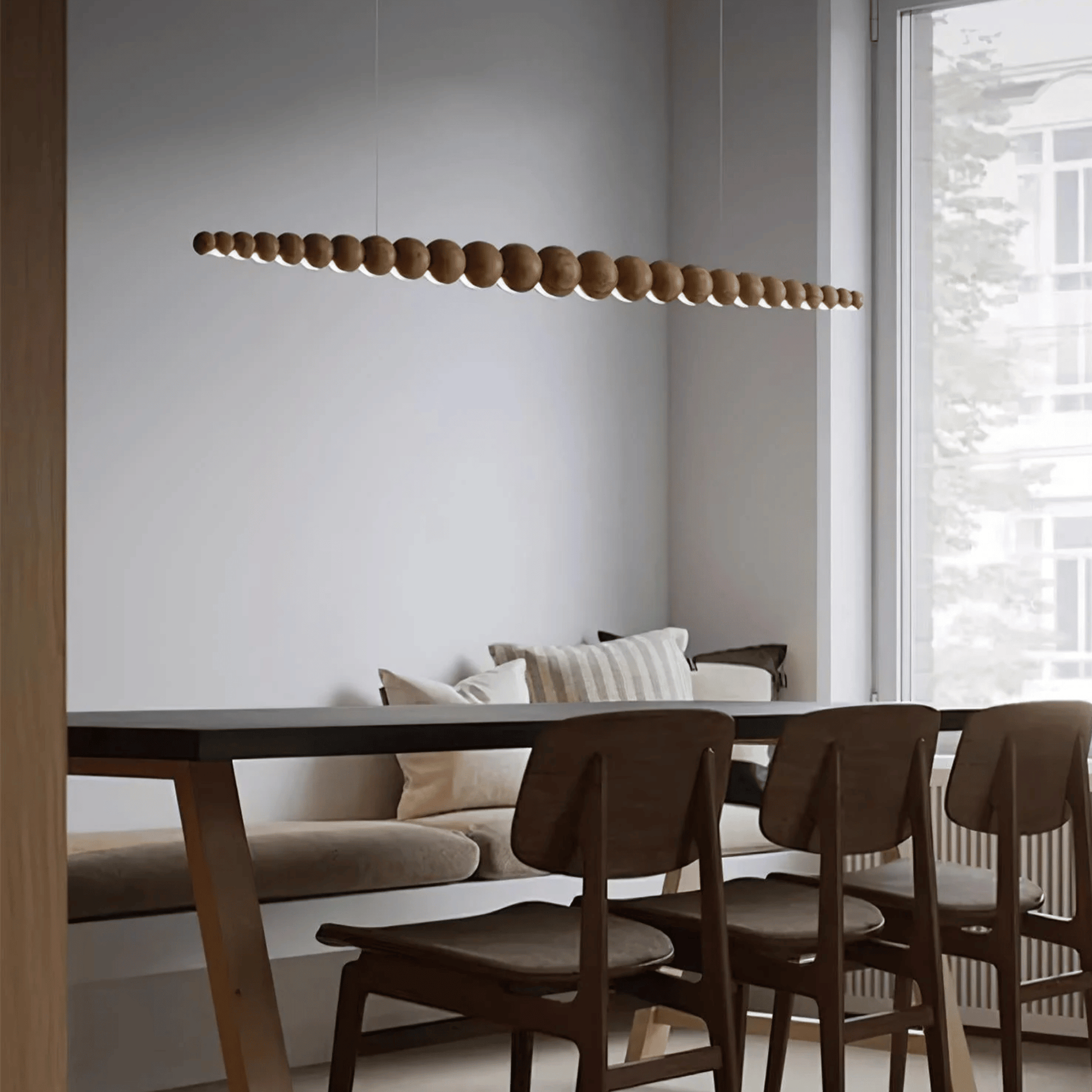 Modern dining area with wooden pendant light, table, and chairs.