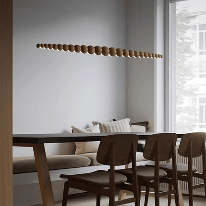 Modern dining area with wooden pendant light, table, and chairs.