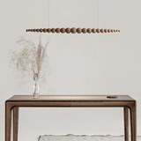 Wooden console table with a vase of dried flowers and a modern pendant light in a minimalistic setting.