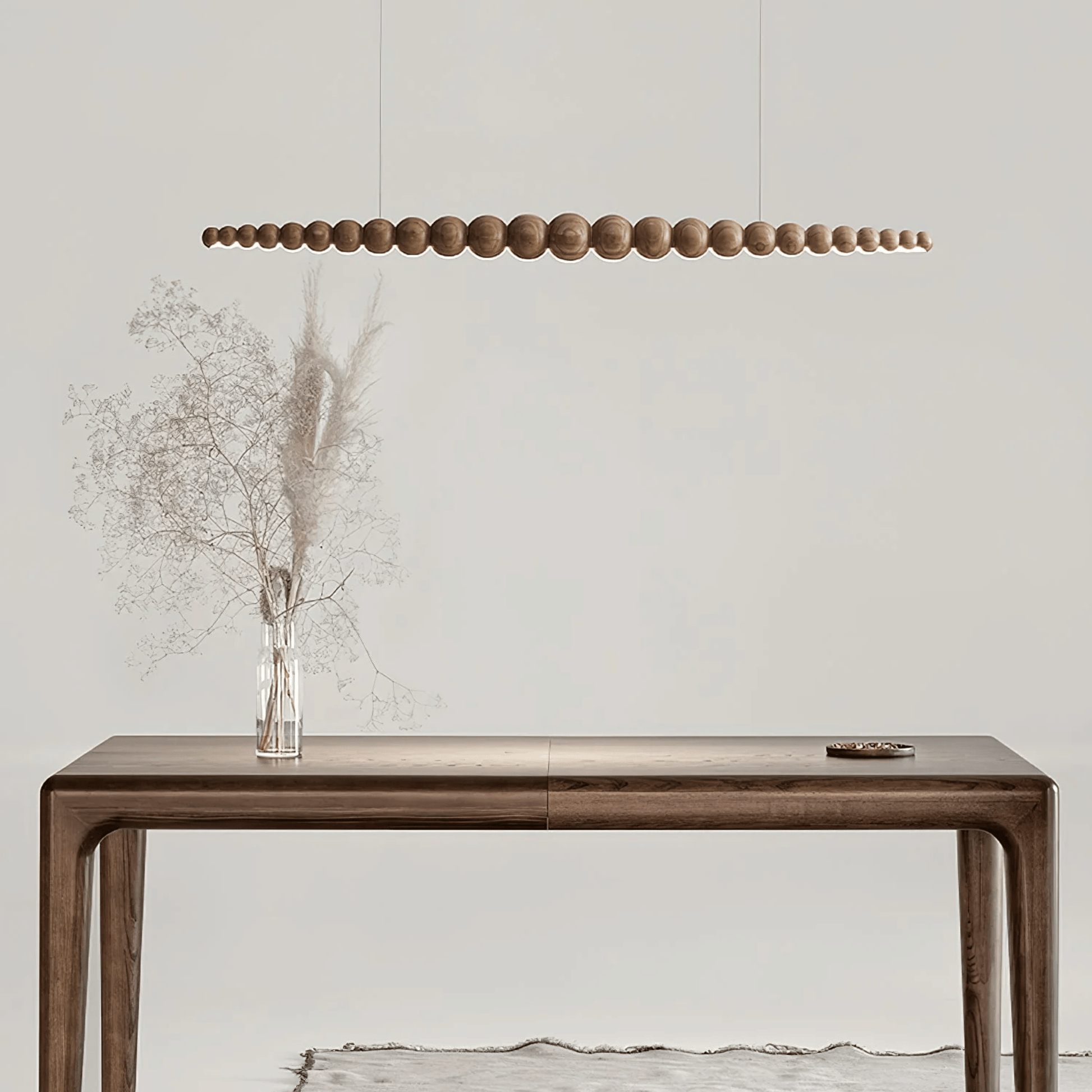 Wooden console table with a vase of dried flowers and a modern pendant light in a minimalistic setting.