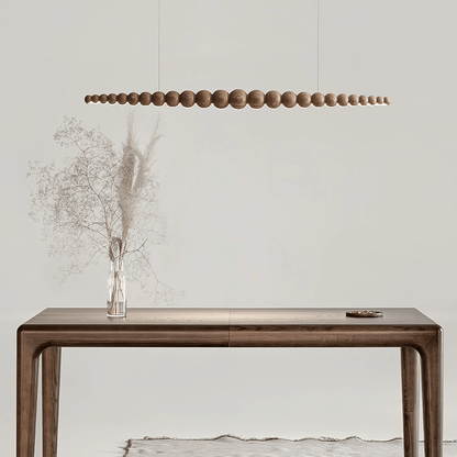 Wooden console table with a vase of dried flowers and a modern pendant light in a minimalistic setting.
