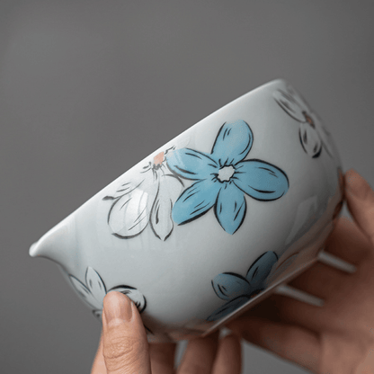 Ceramic bowl with blue floral design held by a hand against a gray background