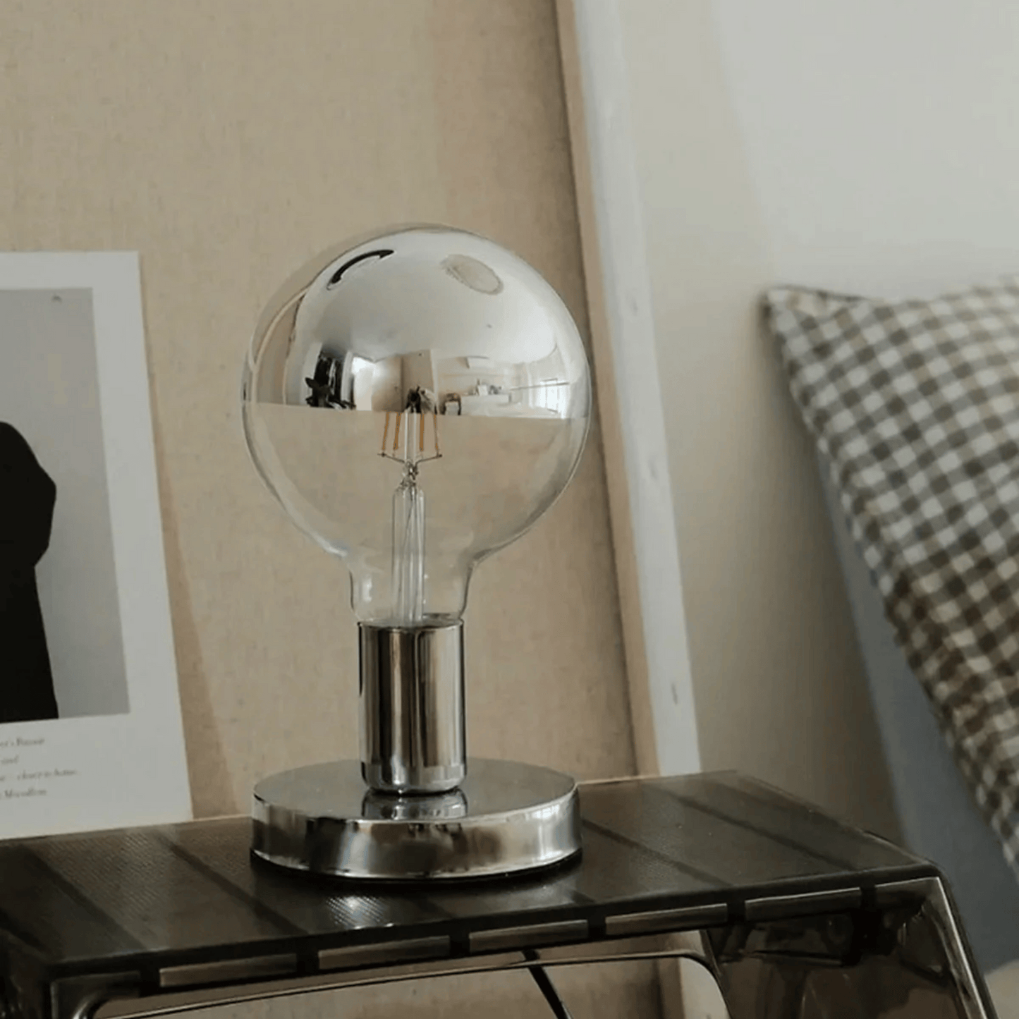 Clear glass light bulb on a metallic base on a table with a neutral background