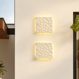 Two square wall lights with textured finish on a light-colored wall.