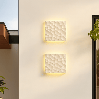 Two square wall lights with textured finish on a light-colored wall.