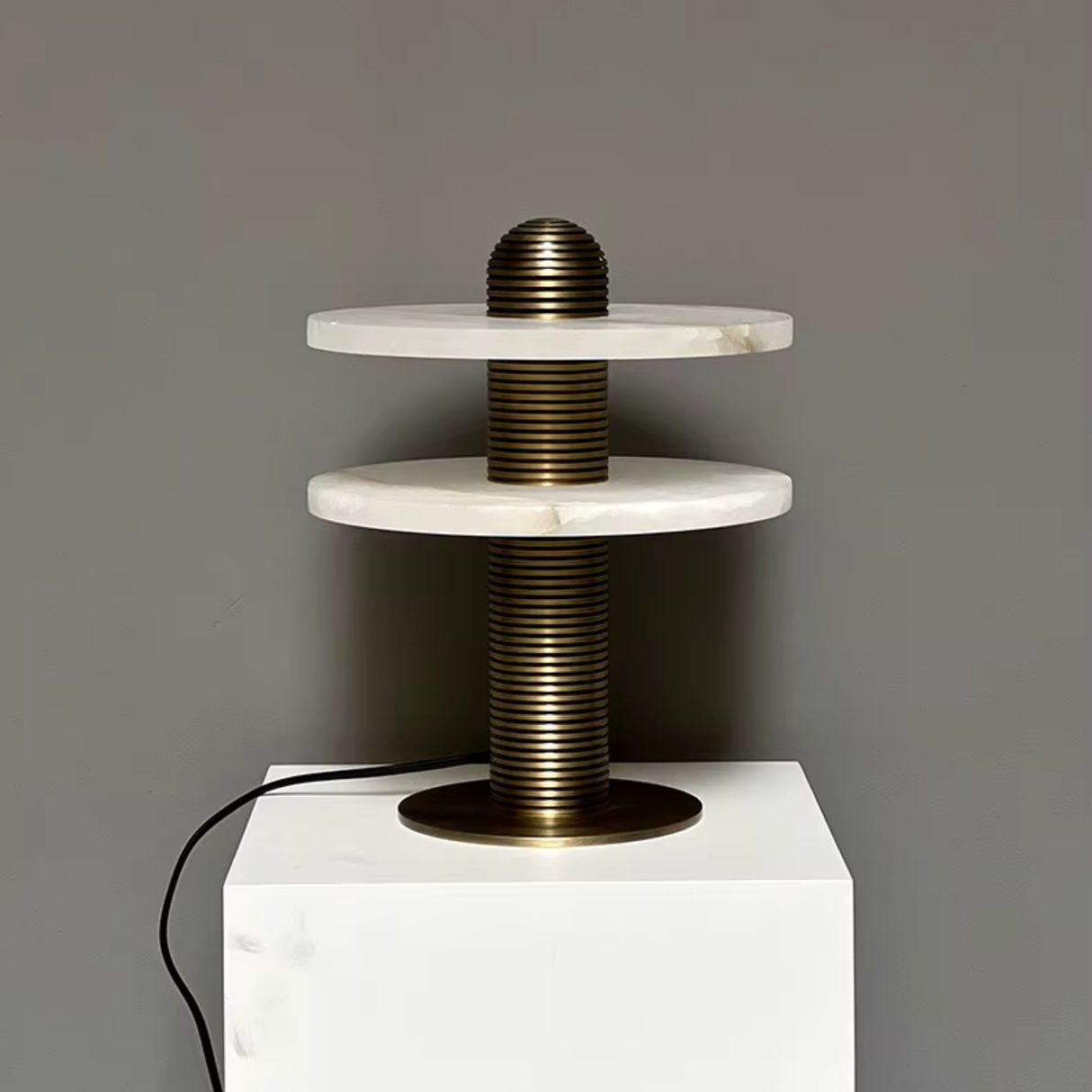 Modern lamp with marble-like top and bronze base on a gray background