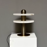 Modern lamp with marble-like top and bronze base on a gray background