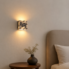 Wall-mounted light fixture casting a warm glow in a bedroom setting.