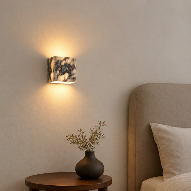 Wall-mounted light fixture casting a warm glow in a bedroom setting.