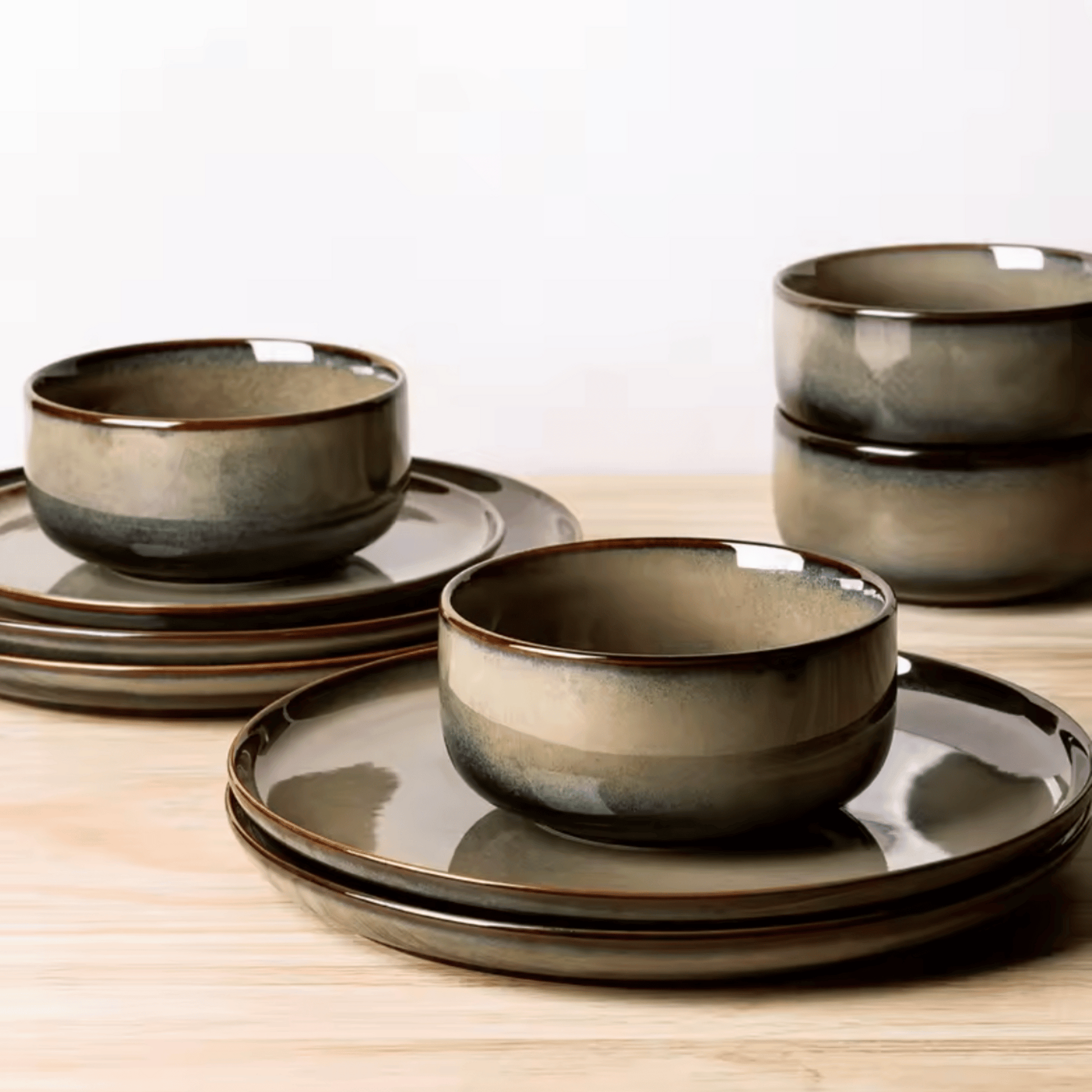 Set of ceramic bowls and plates with a brownish-grey glaze on a wooden surface.