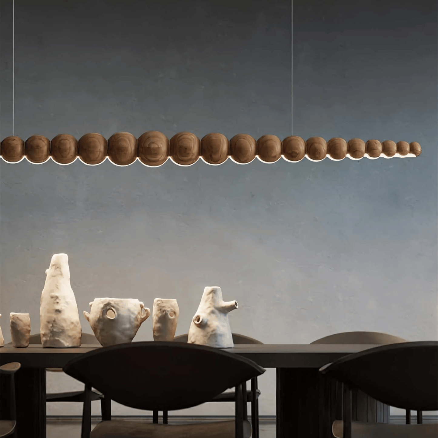 Modern pendant light fixture hanging above a dining table with decorative sculptures.
