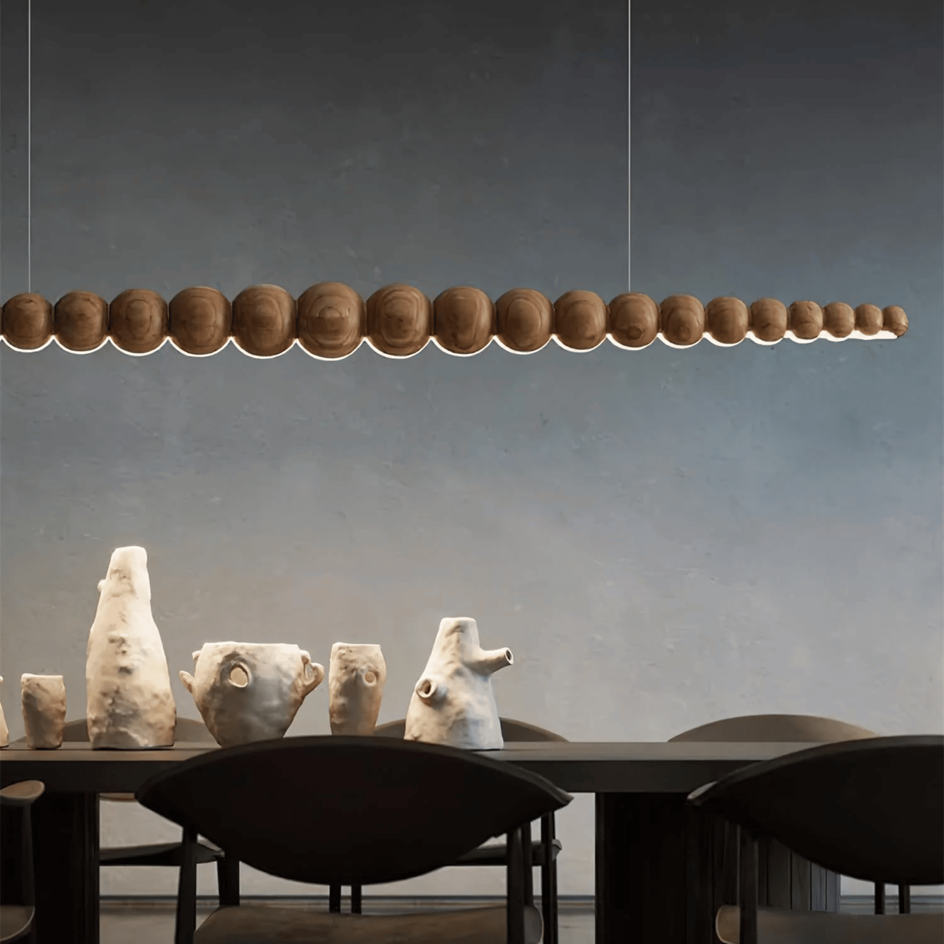 Modern pendant light fixture hanging above a dining table with decorative sculptures.