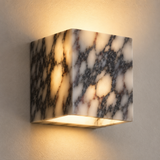 Marble-patterned wall sconce casting a warm glow on a neutral wall.