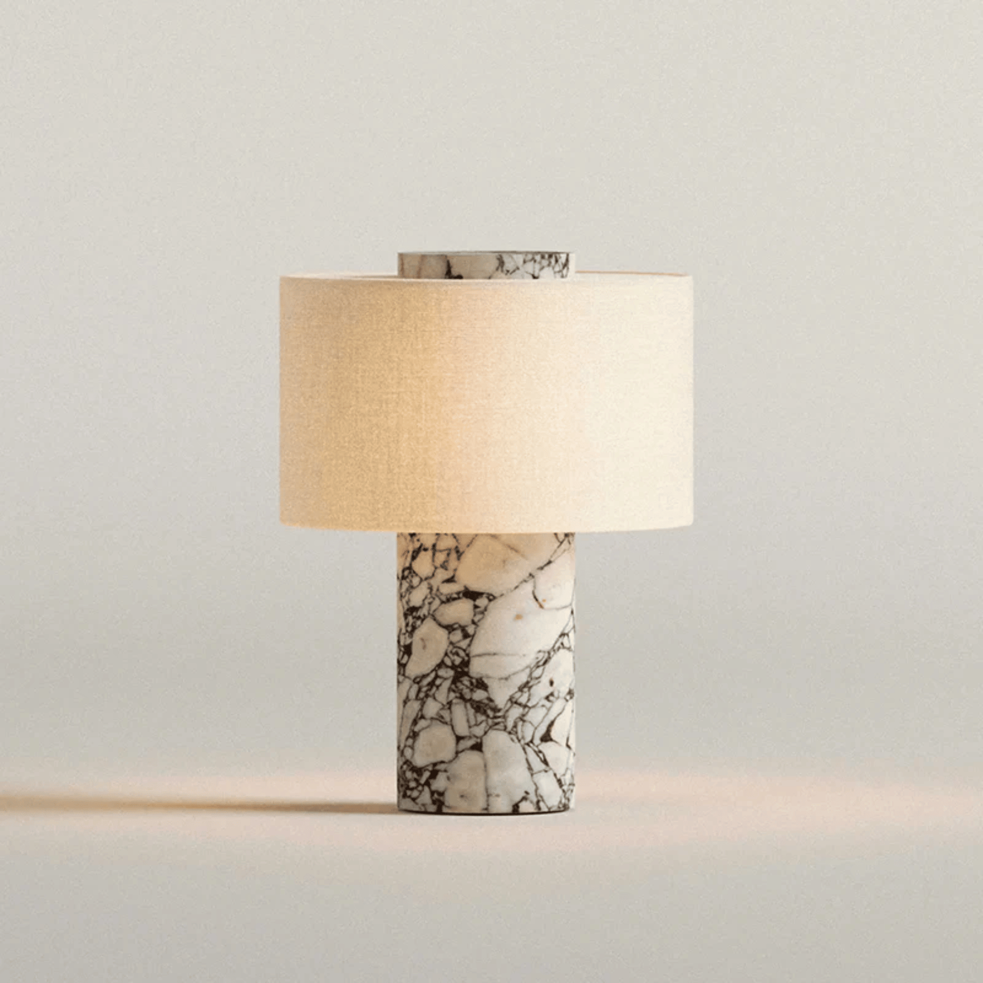 Table lamp with marble base and beige shade on a light gray background