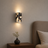 Wall sconce lighting a room with a vase and plant on a nightstand.