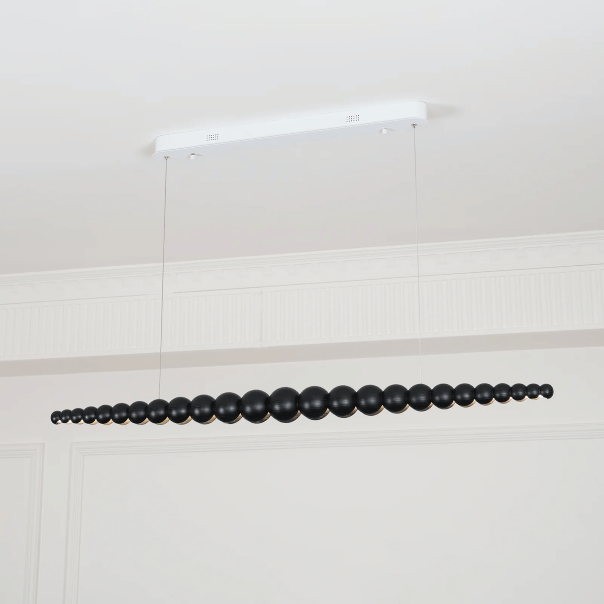 Black beaded chandelier hanging from a white ceiling