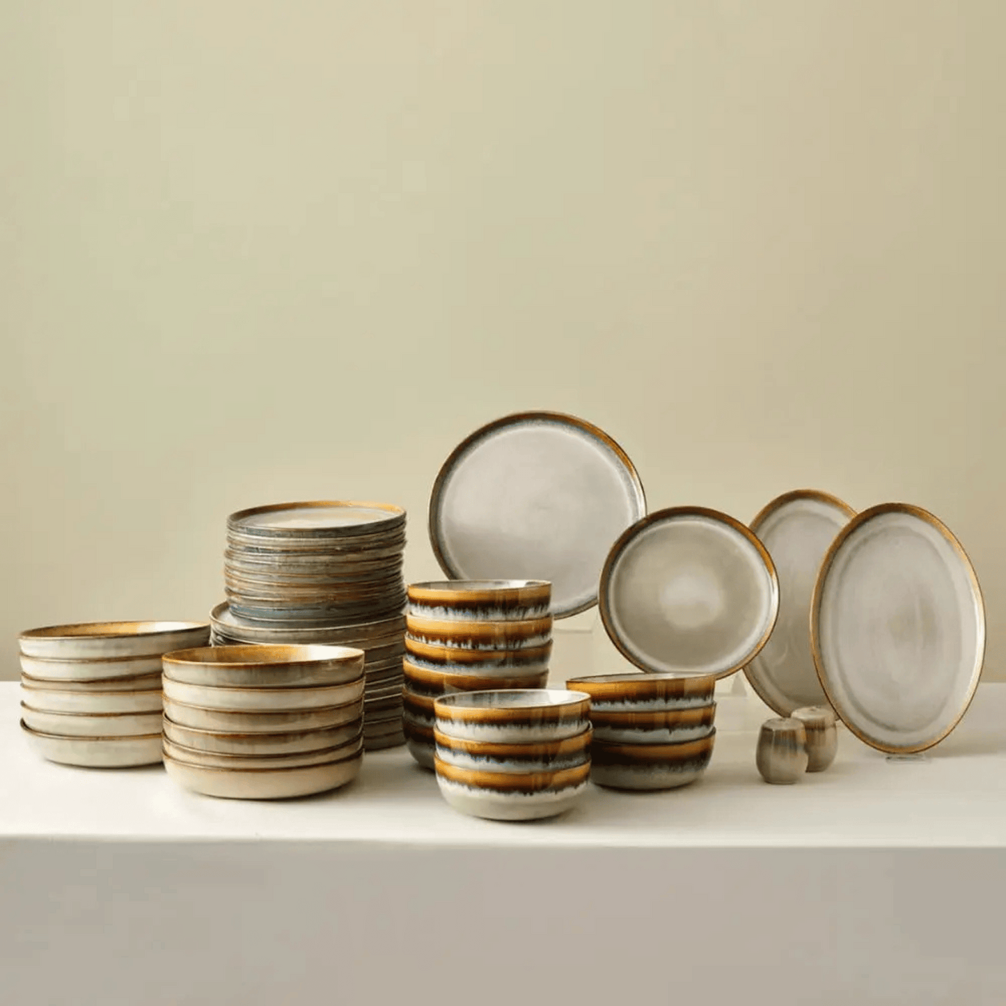 Set of ceramic dinnerware with brown and beige glaze on a neutral background