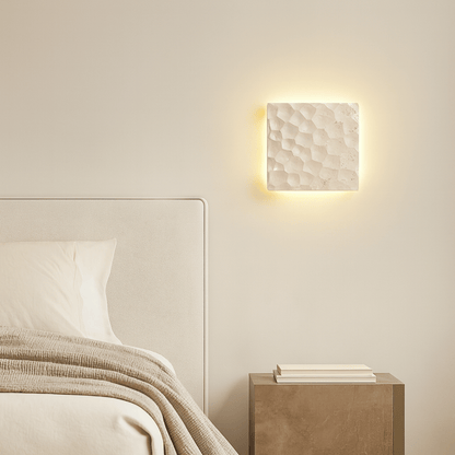 Bedroom with a textured wall light fixture and wooden nightstand.