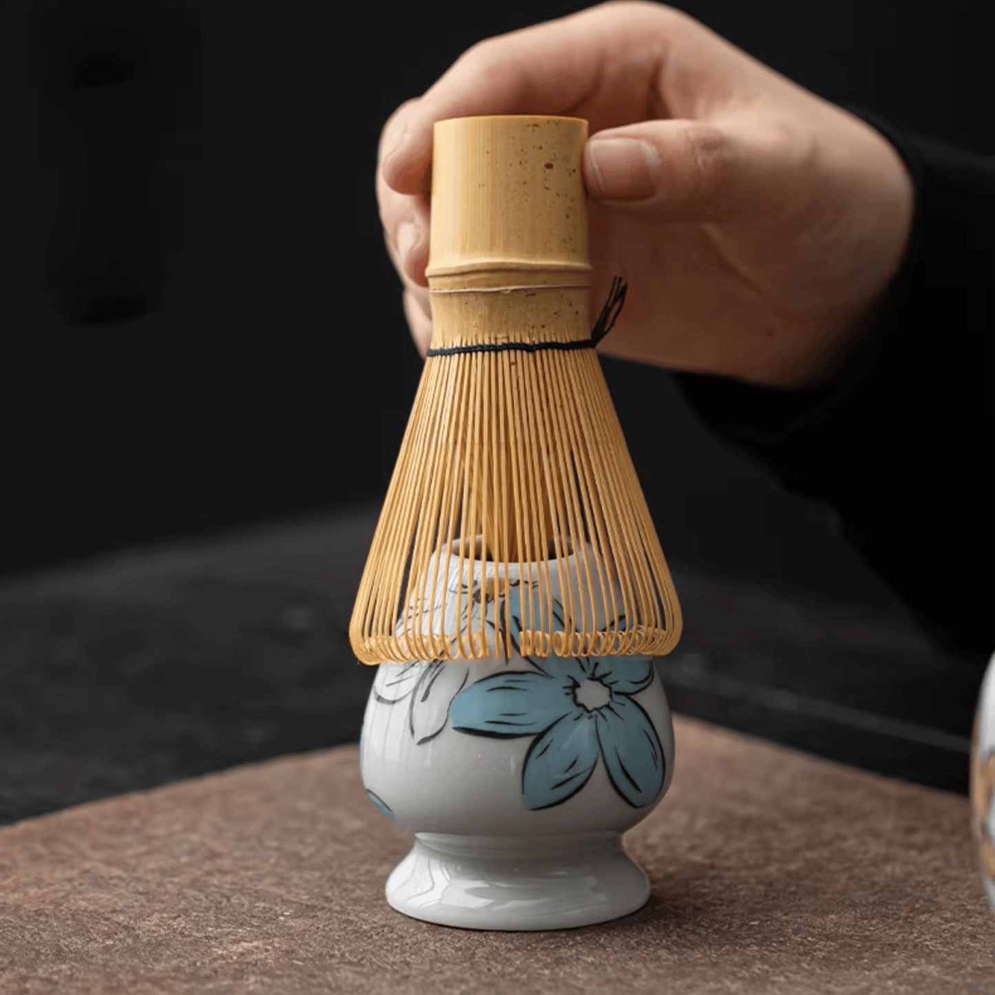 Ceramic whisk with bamboo handle on a dark background