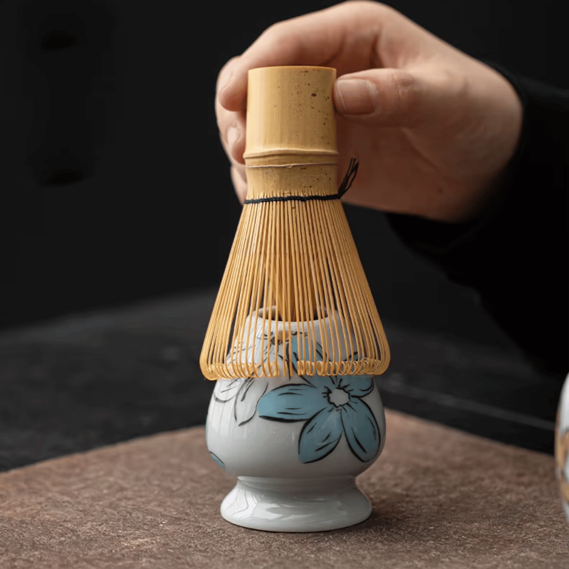 Ceramic whisk with bamboo handle on a dark background