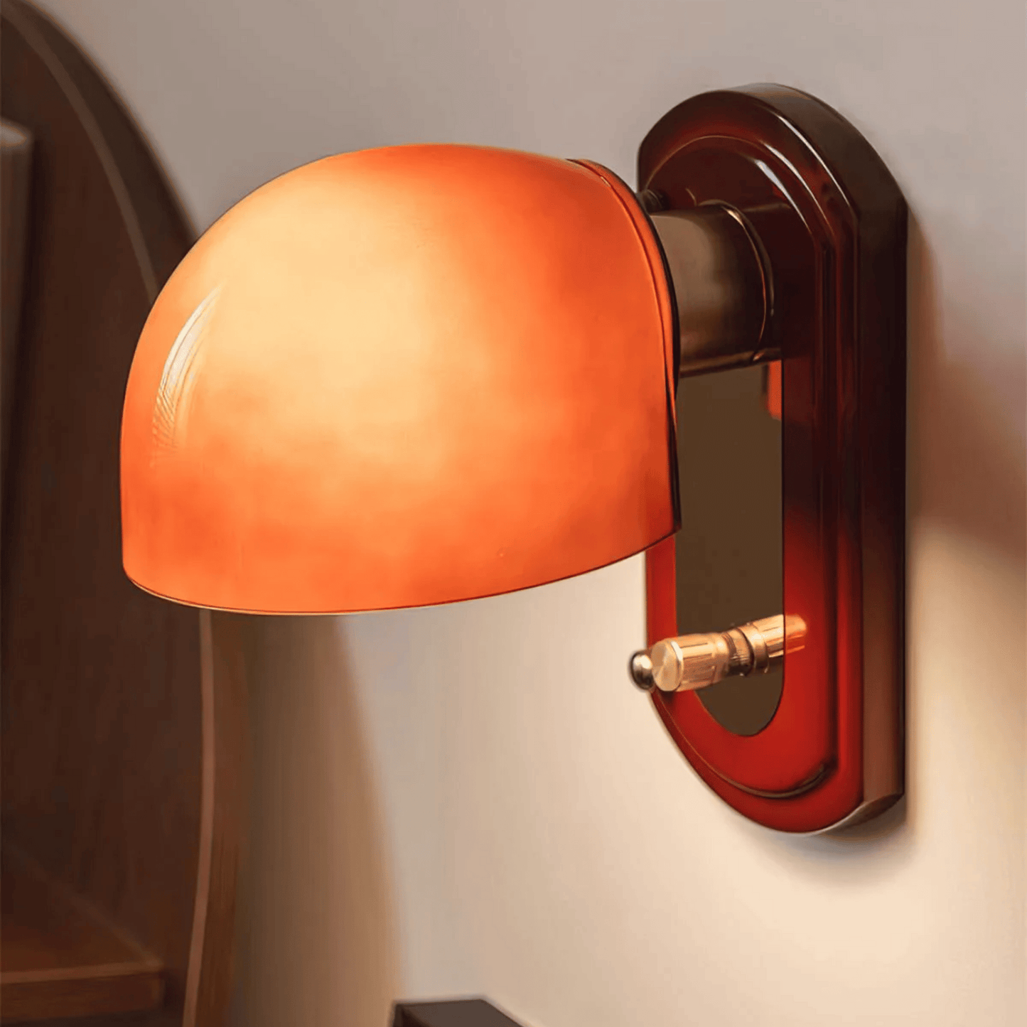 Wall-mounted lamp with orange glass shade and brown metal fixture on a neutral wall.
