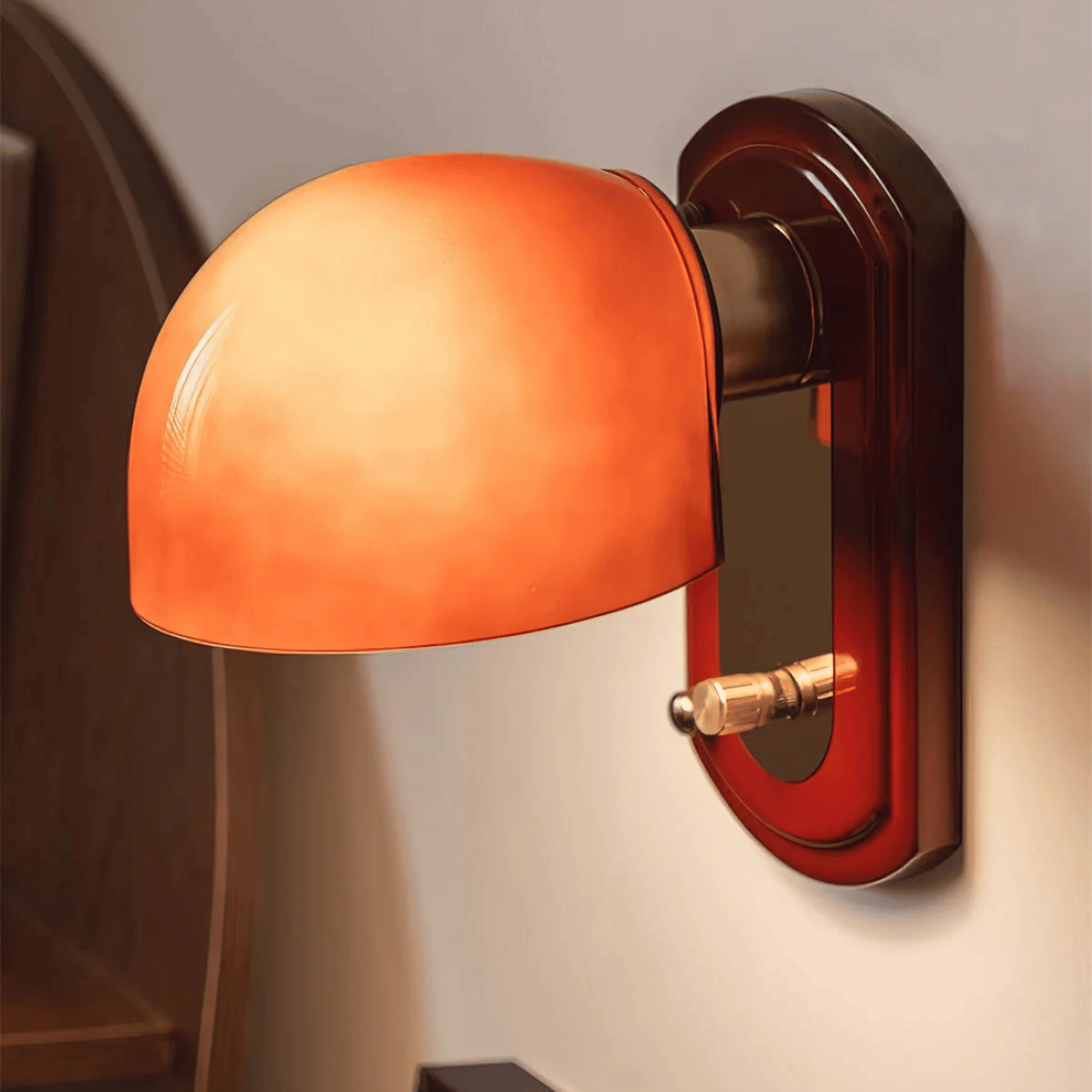 Wall-mounted lamp with orange glass shade and brown metal fixture on a neutral wall.