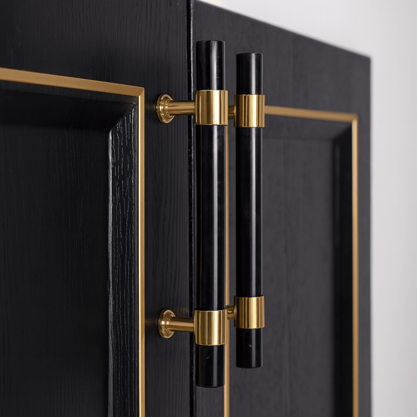 Black cabinet handles with gold accents on a black cabinet door.