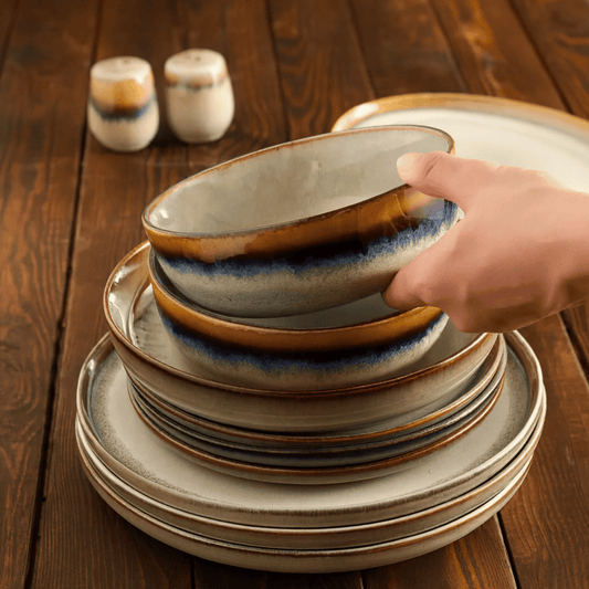 Stack of ceramic plates with a hand reaching for one on a wooden table
