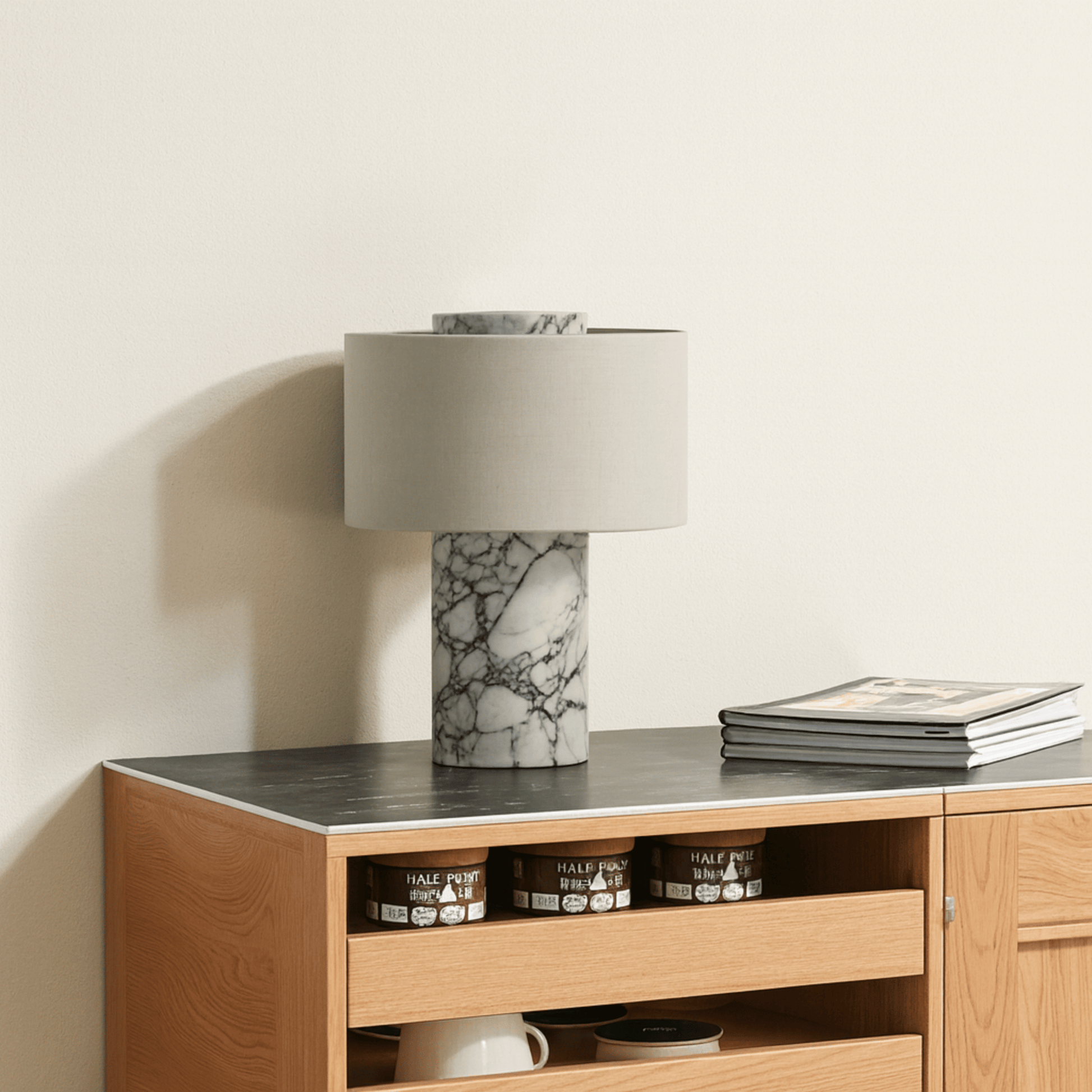 Wooden sideboard with marble lamp and books on a neutral background
