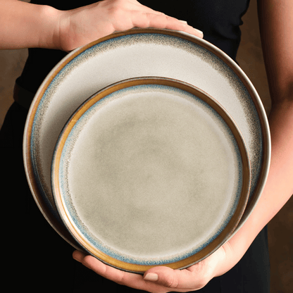 Two ceramic plates held by hands with a blurred background