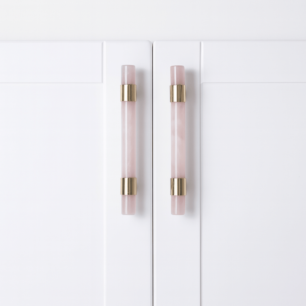 White cabinet doors with pink and gold handles on a white background