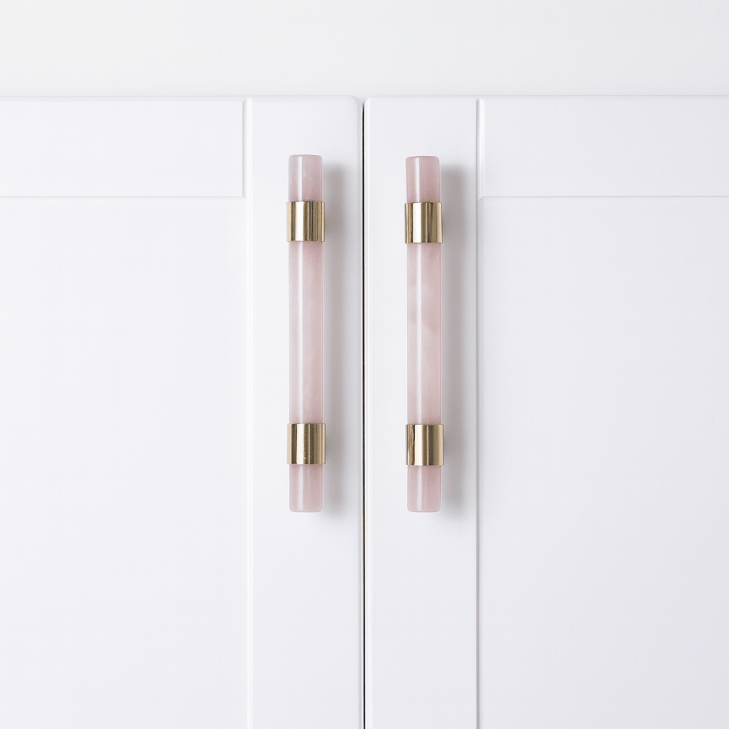 White cabinet doors with pink and gold handles on a white background
