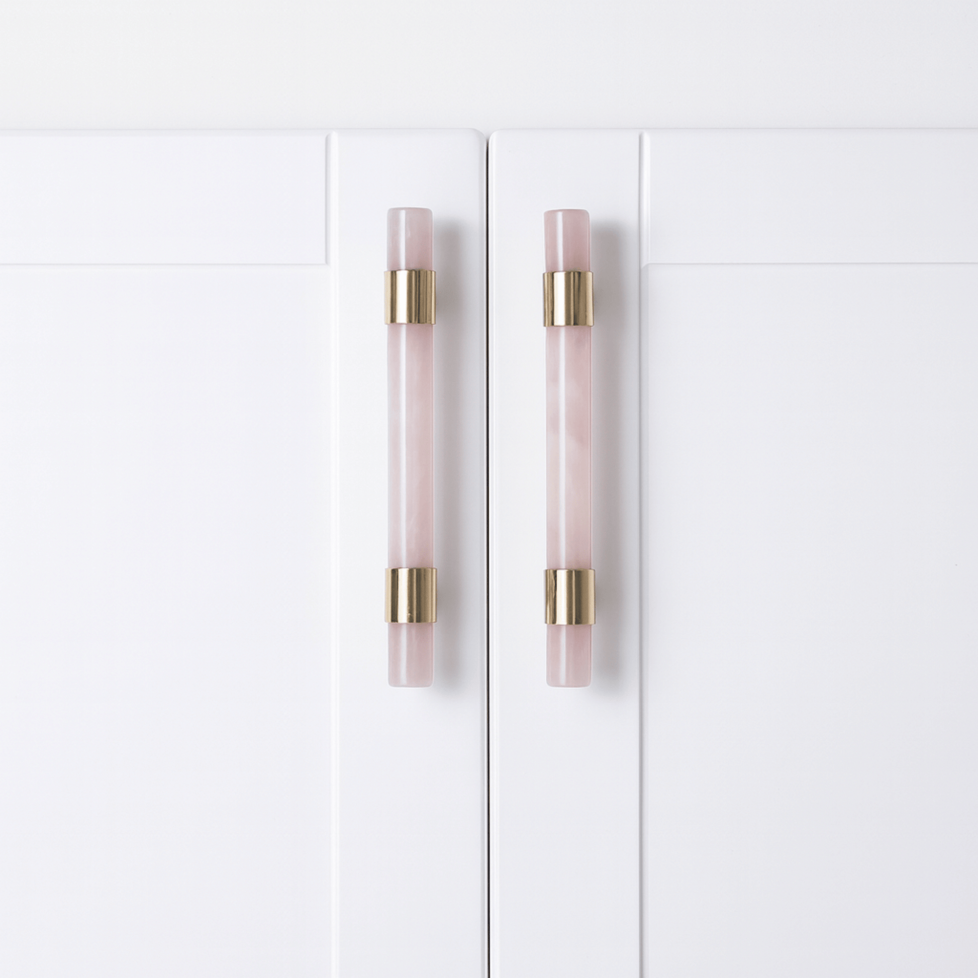 White cabinet doors with pink and gold handles on a white background